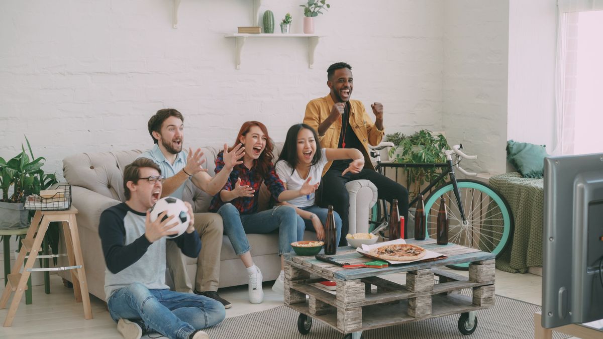 Grupo de amigos vibrando com um jogo de futebol na TV